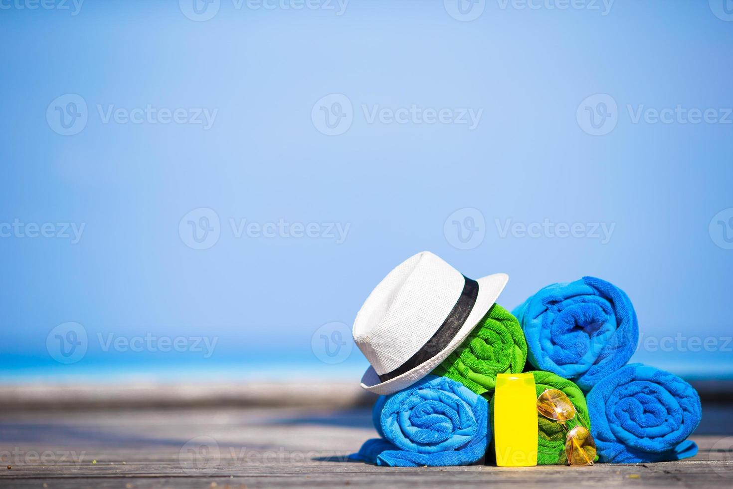 Beach and summer vacation accessories concept - close-up of colorful towels, hat, swimming goggles and sunblock photo