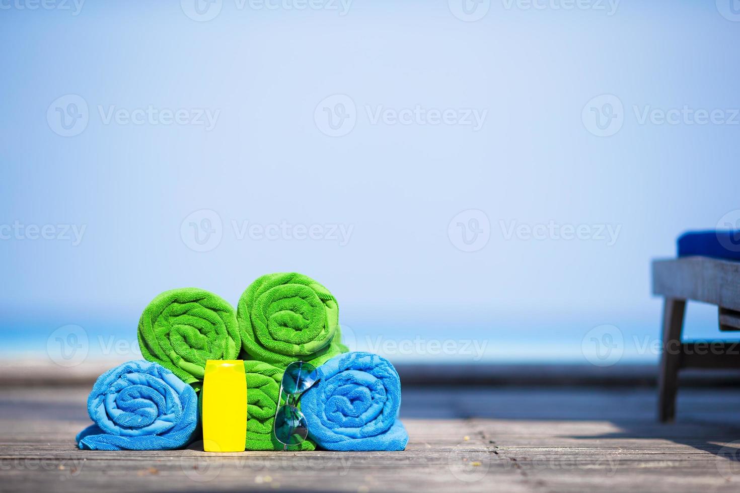 Beach and summer vacation accessories concept - close-up of colorful towels, swimming goggles and sunblock photo