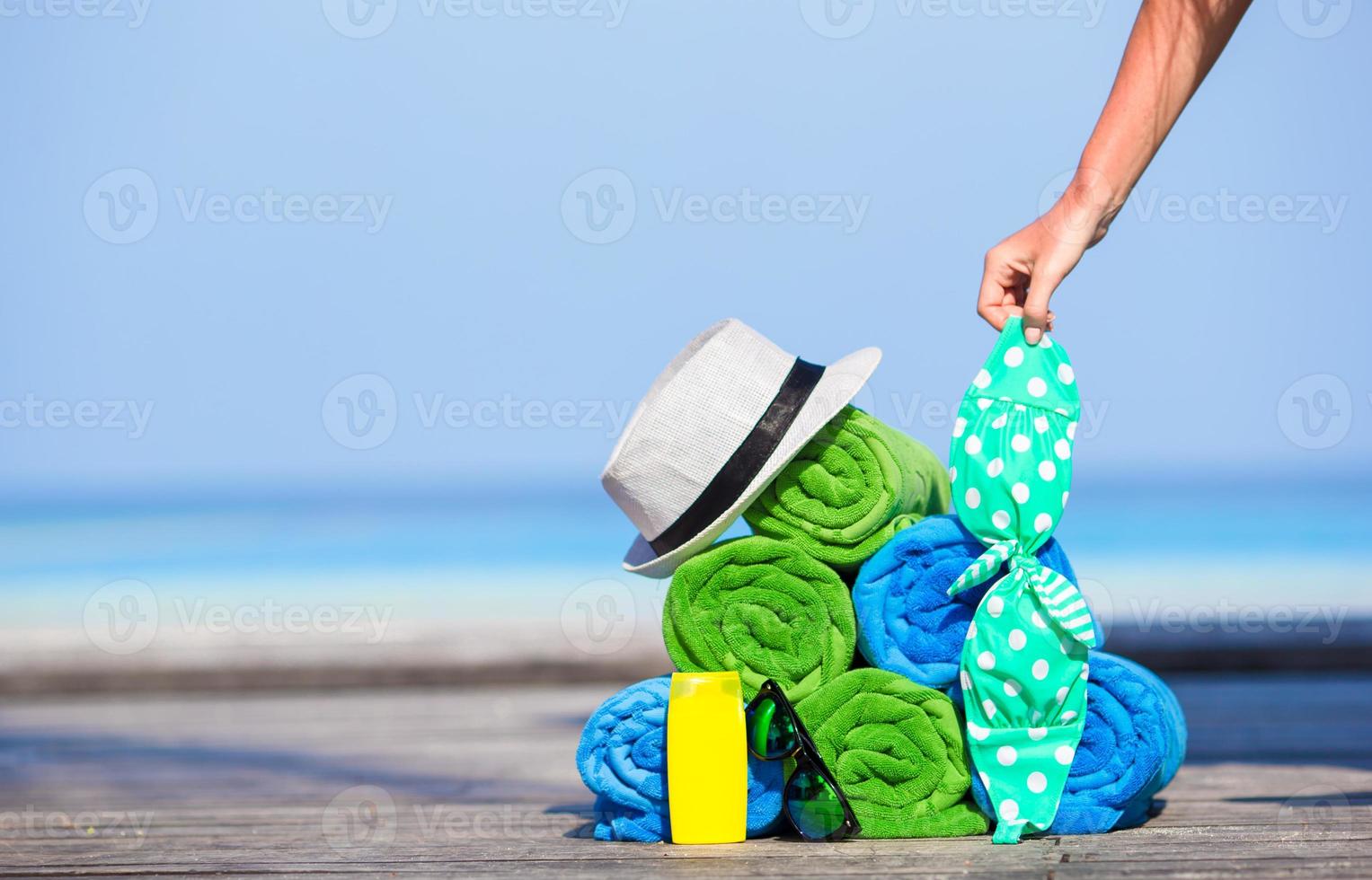 Beach and summer vacation accessories concept - close-up of colorful towels, hat, bag and sunblock photo