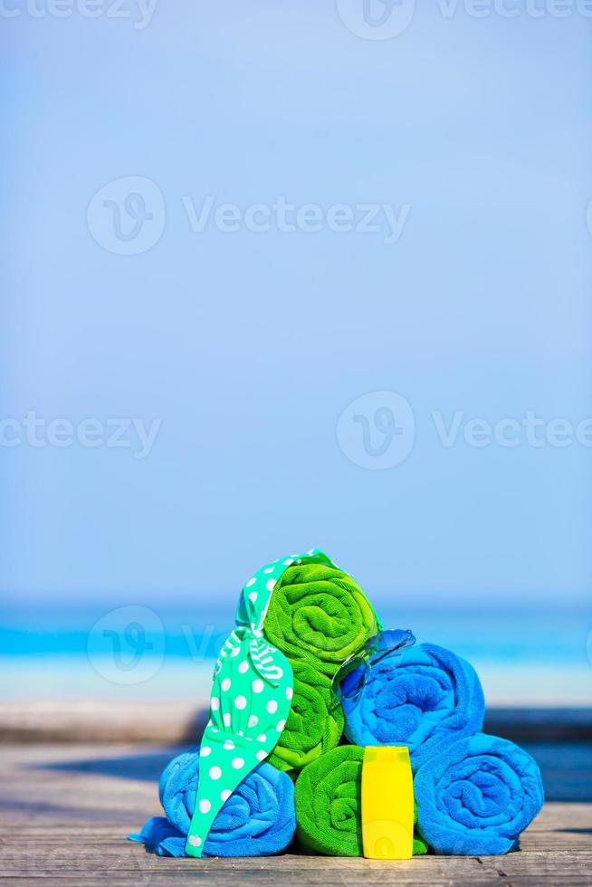 Beach and summer vacation accessories concept - close-up of colorful towels, swimming goggles and sunblock photo