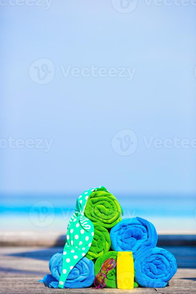 Beach and summer vacation accessories concept - close-up of colorful towels, hat, bag and sunblock photo