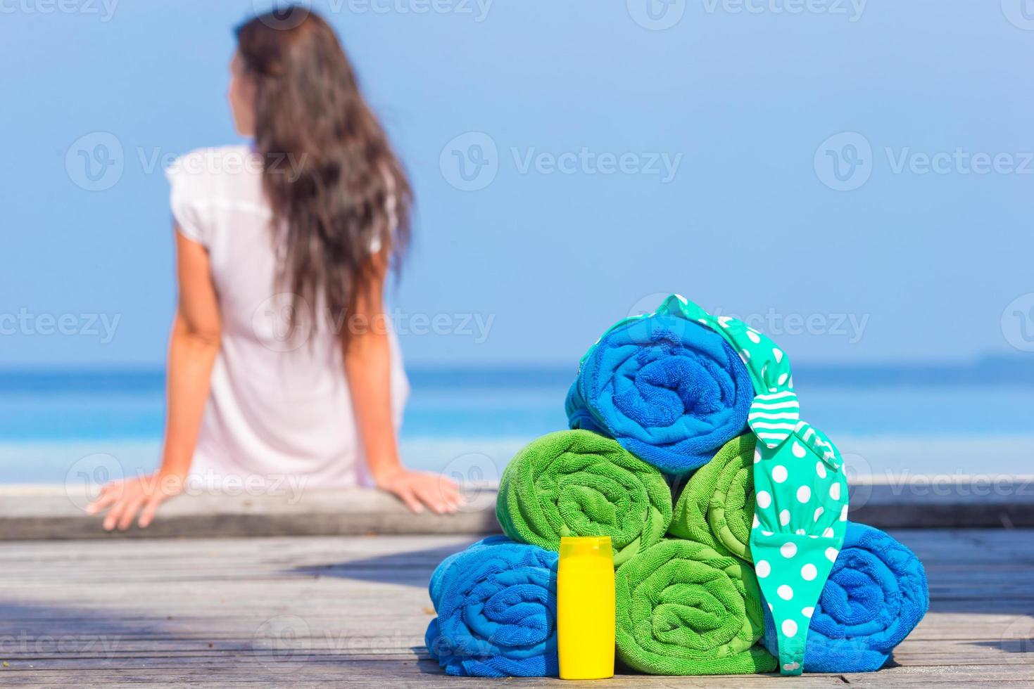 Beach and summer accessories concept - colorful towels, swimsuit and sunsblock background beautiful woman photo