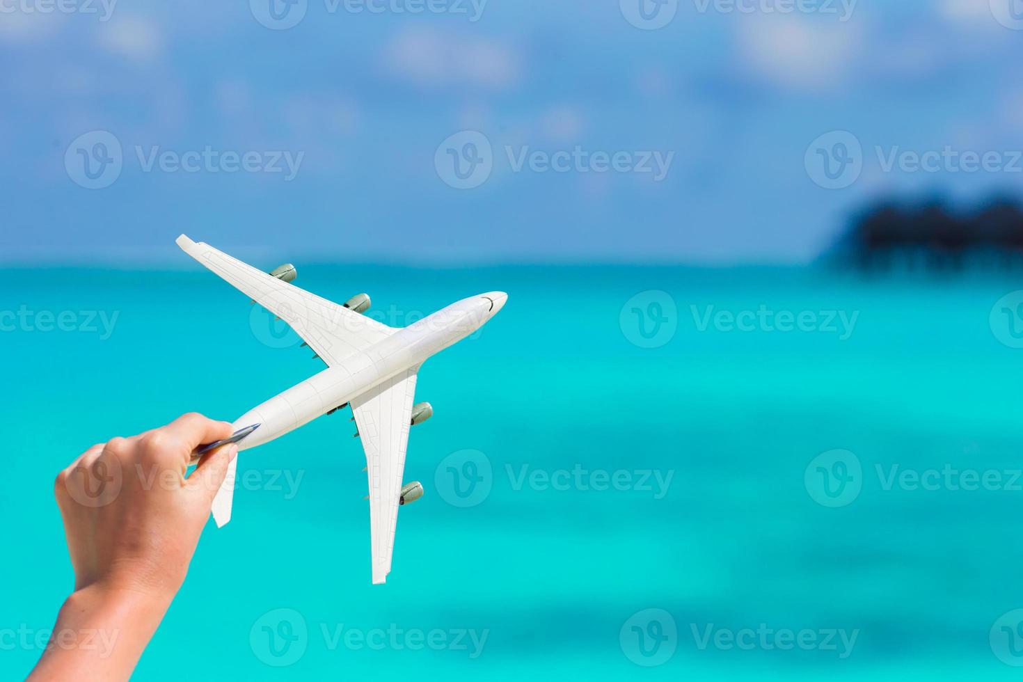 Small white miniature of an airplane on background of turquoise sea photo