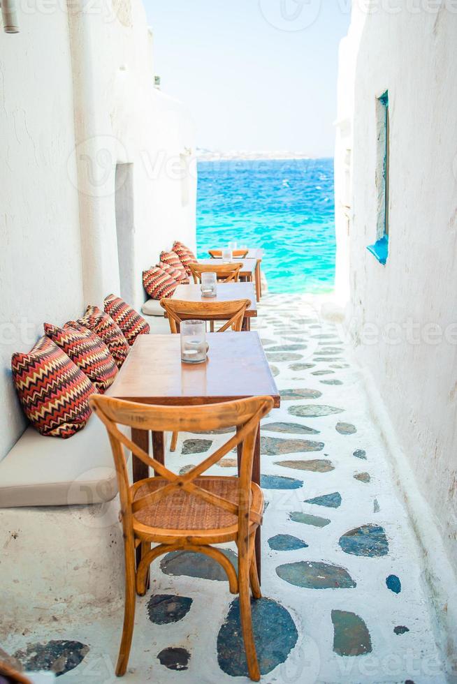 Benches with pillows in a typical greek outdoor cafe in Mykonos with amazing sea view on Cyclades islands photo