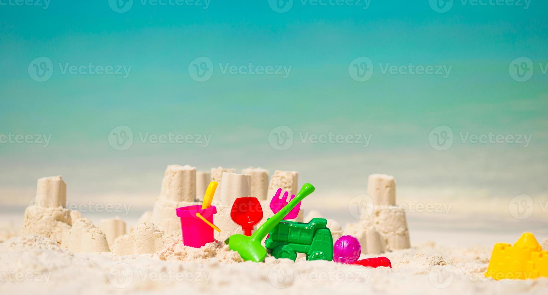 Sandcastle at white beach with plastic kids toys photo