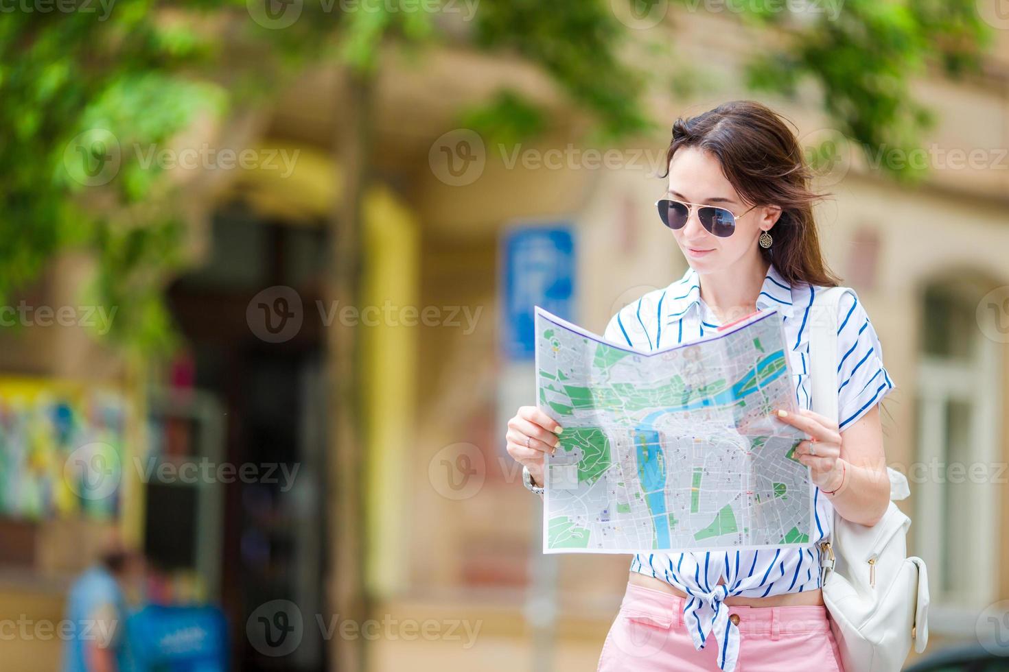 mujer joven feliz con un mapa de la ciudad en europa. viaje mujer turista con mapa en praga al aire libre durante las vacaciones en europa. foto