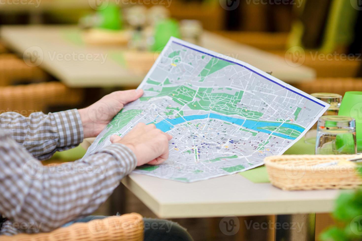 joven europeo caucásico con mapa de la ciudad en un café al aire libre. retrato de atractivo joven turista a la hora del almuerzo foto