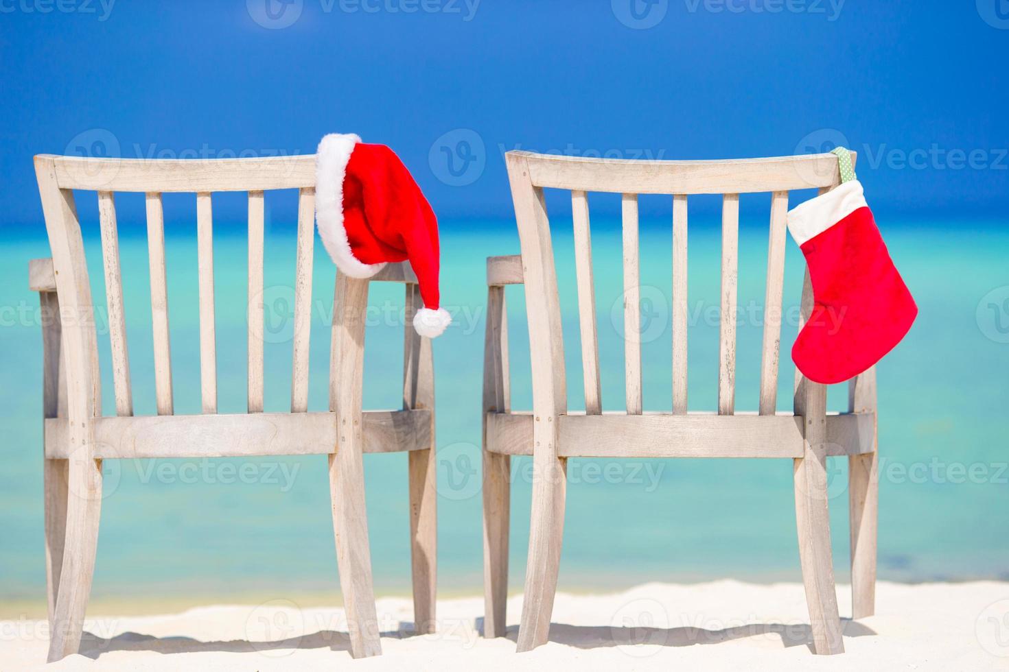 Red Christmas stocking and Santa Hat on chair at tropical white beach photo