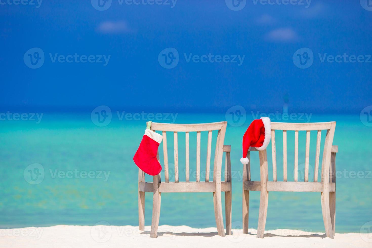 Red Christmas stocking and Santa Hat on chair at tropical white beach photo