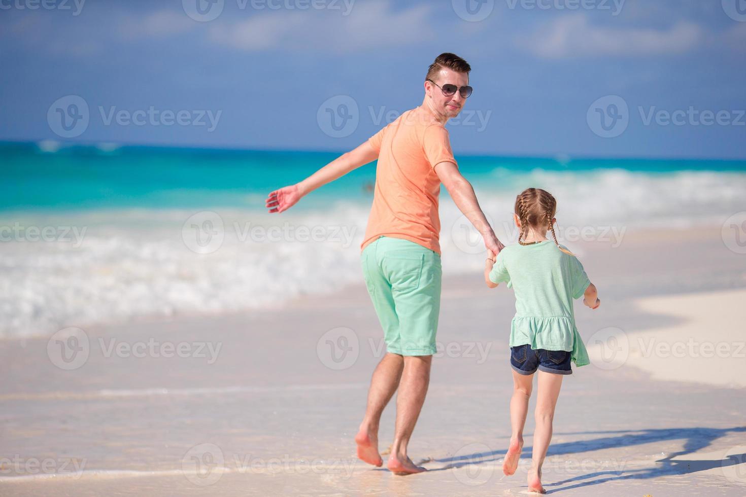 Happy family of dad and little girl running on the seashore and having a lot of fun photo
