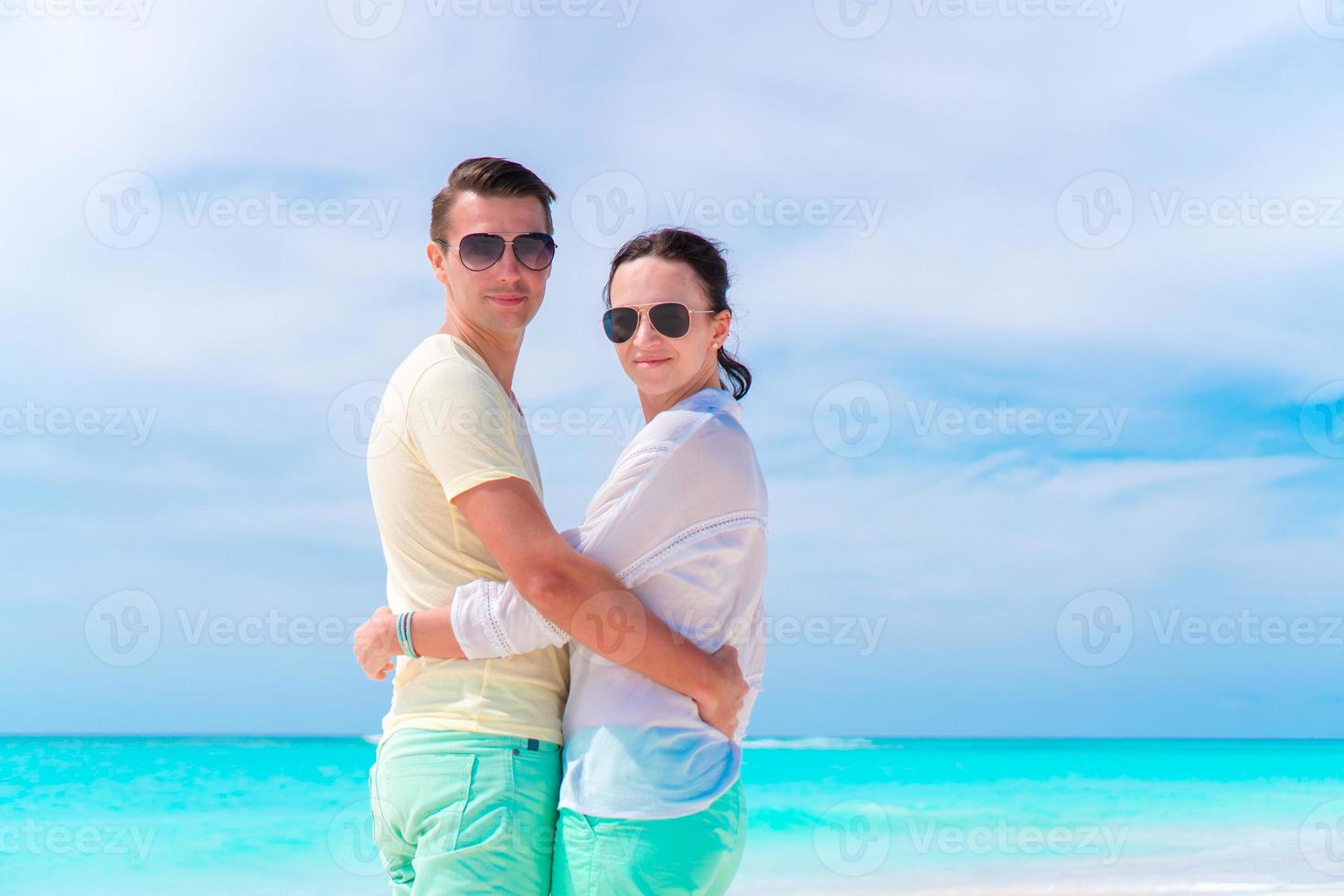 Young couple on white beach during summer vacation. Happy lovers enjoy their honeymoon photo