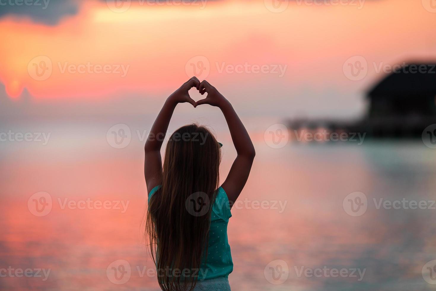 silueta de corazón hecha a mano por niños al atardecer foto