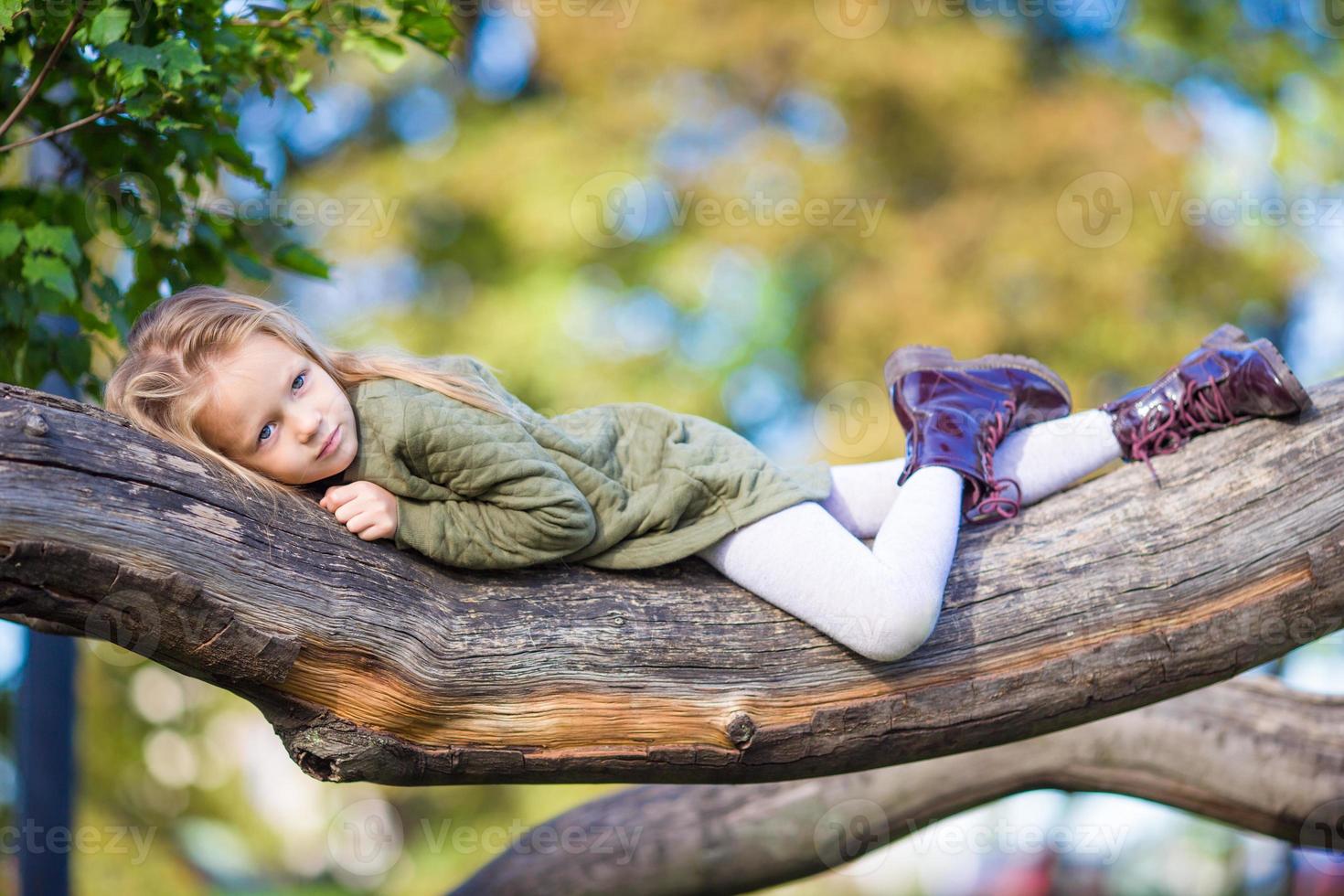 Adorable little girl outdoors at beautiful warm day in autumn park photo