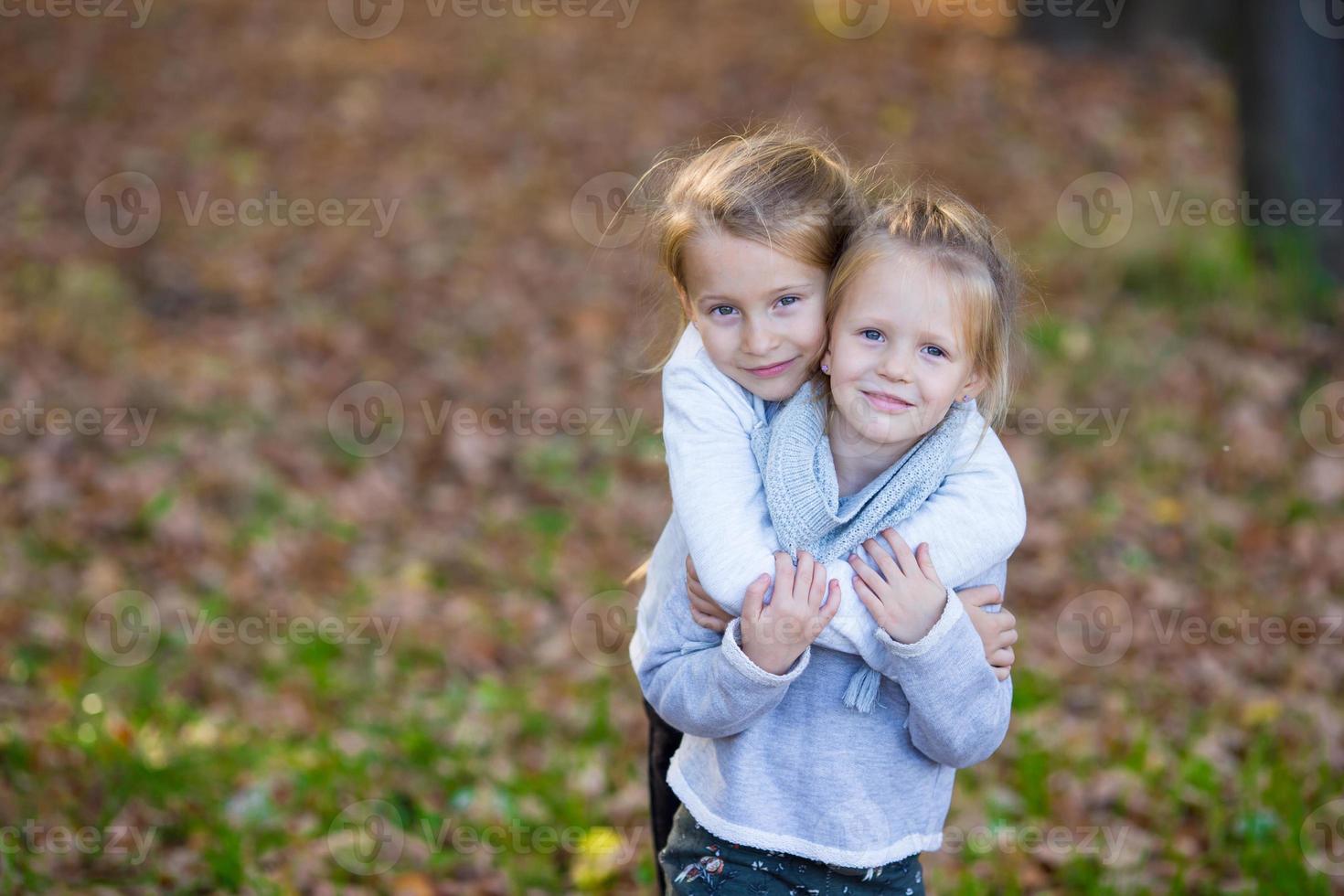 Little girls having fun in beautiful autumn park outdoor photo