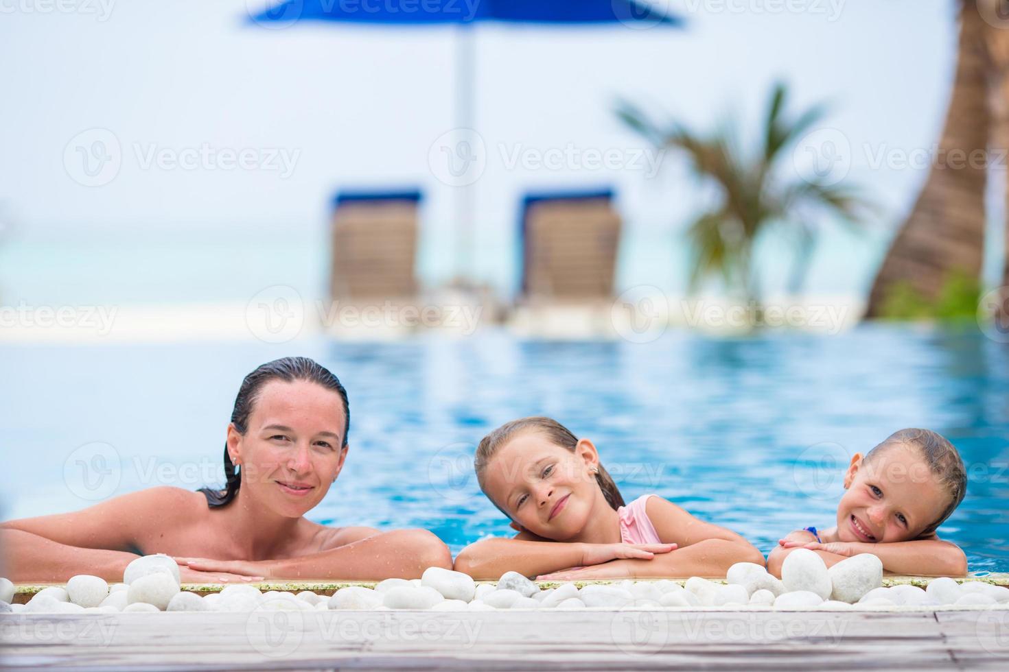 Mother and two little kids enjoying summer vacation in luxury swimming pool photo