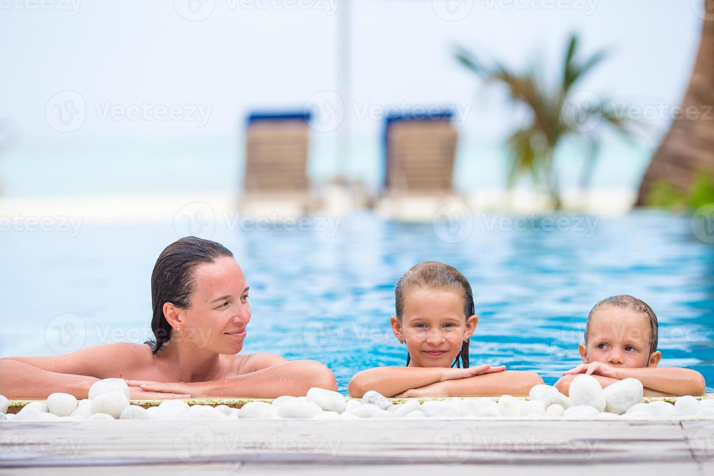 Adorable girl and happy mom enjoying vacation in outdoor swimming pool photo