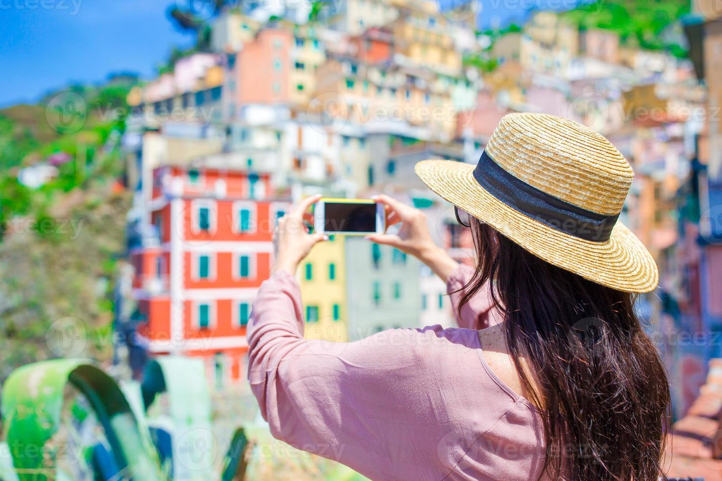 Young woman take a photo of beautiful view at old village in Cinque Terre, Liguria, Italy. European italian vacation.