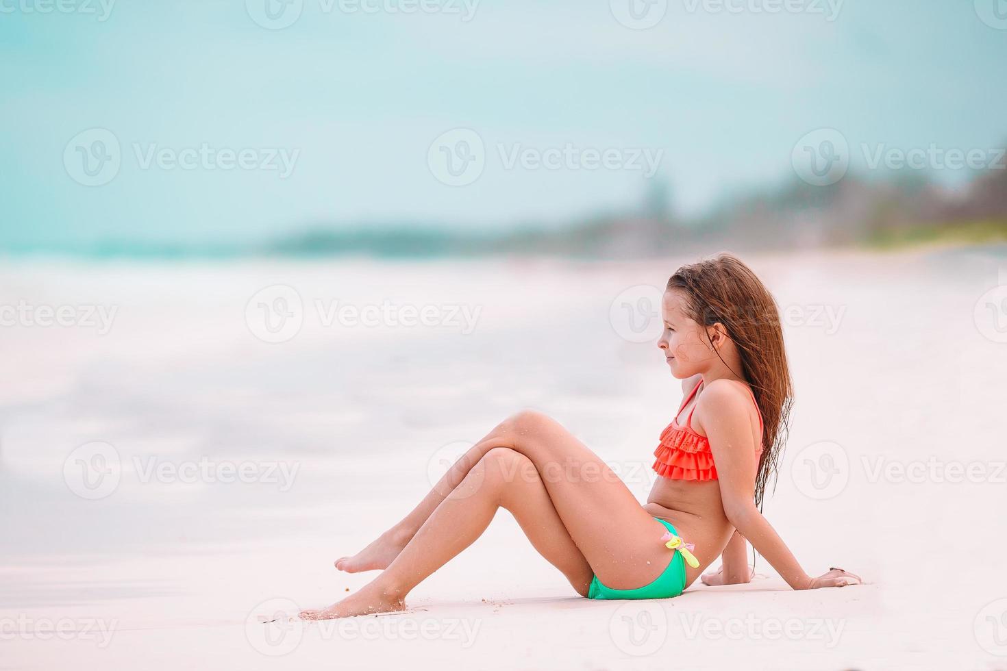 Happy little girl walking at beach during caribbean vacation photo