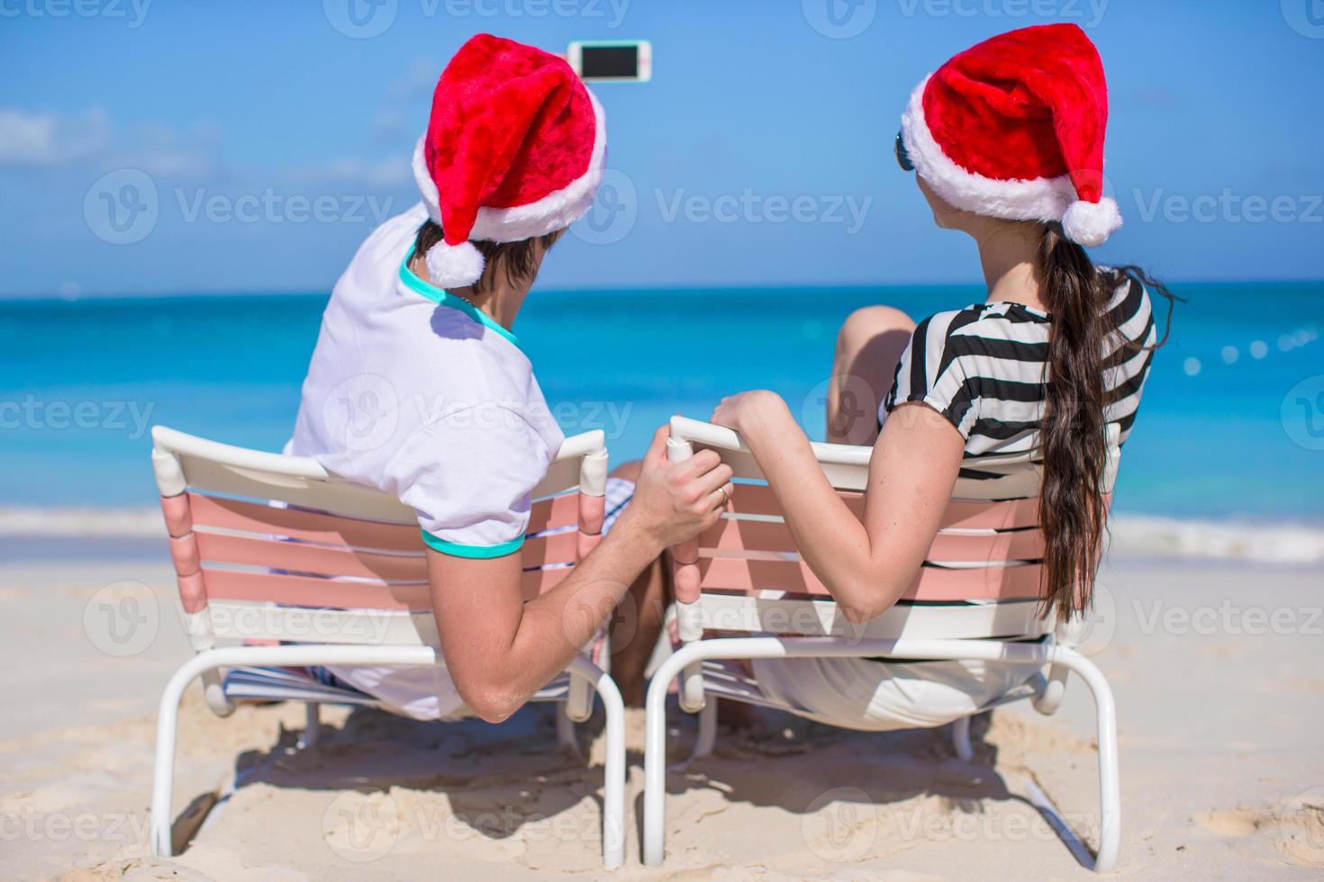 Young happy couple in red Santa hats taking a photo