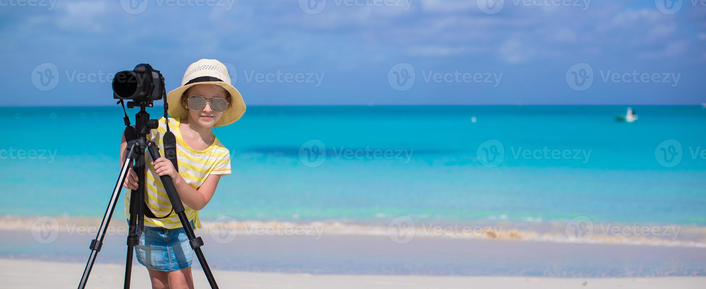 niña disparando con cámara en trípode durante sus vacaciones de verano foto