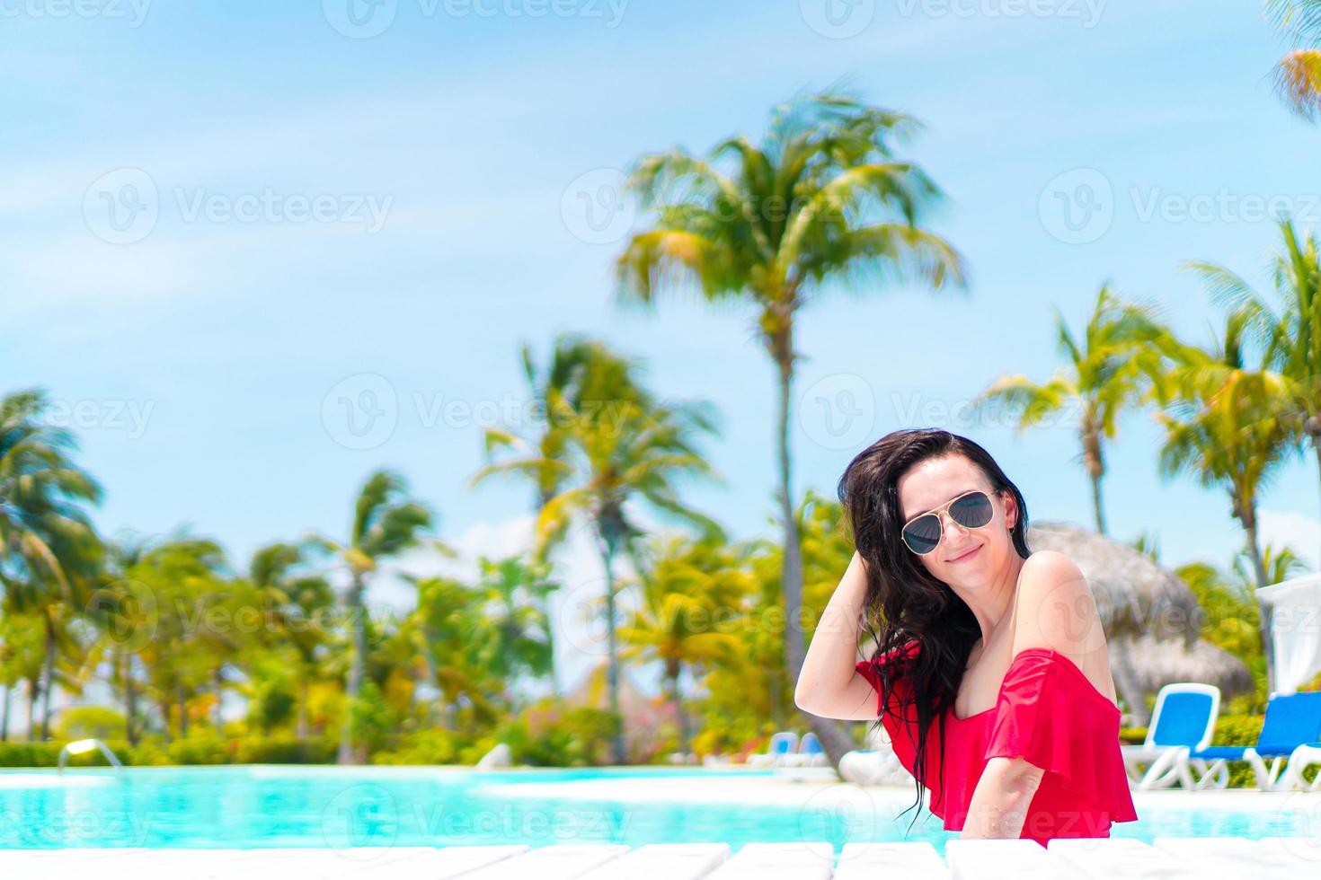 Beautiful young woman relaxing in swimming pool. Happy girl in outdoor pool at luxury hotel photo
