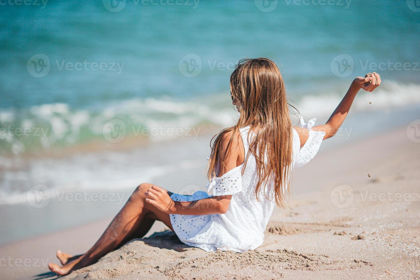 Back view of adorable little girl with long hair in white dress on