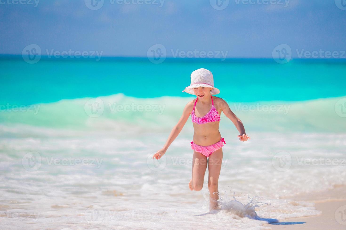 Adorable little girl at beach having a lot of fun in shallow water photo