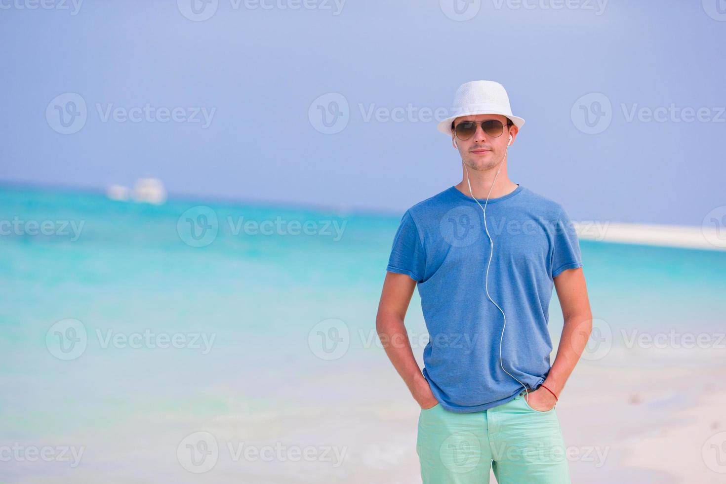 Young man on beach vacation. Happy boy enjoy beach and warm weather while walking along the ocean photo