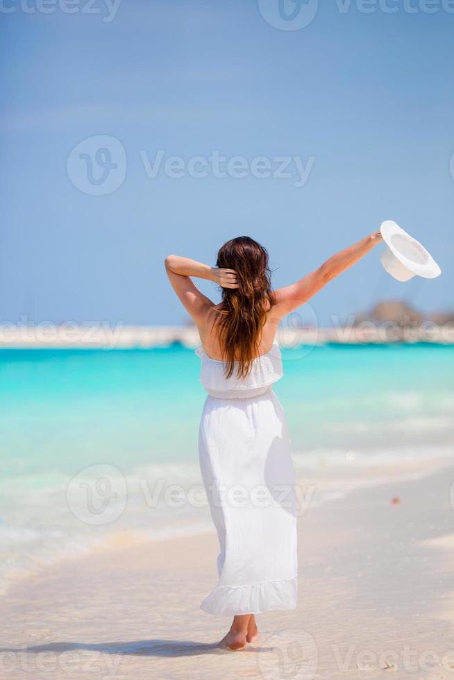 Young beautiful woman on beach vacation. Happy girl enjoy beach and warm weather while walking along the ocean photo