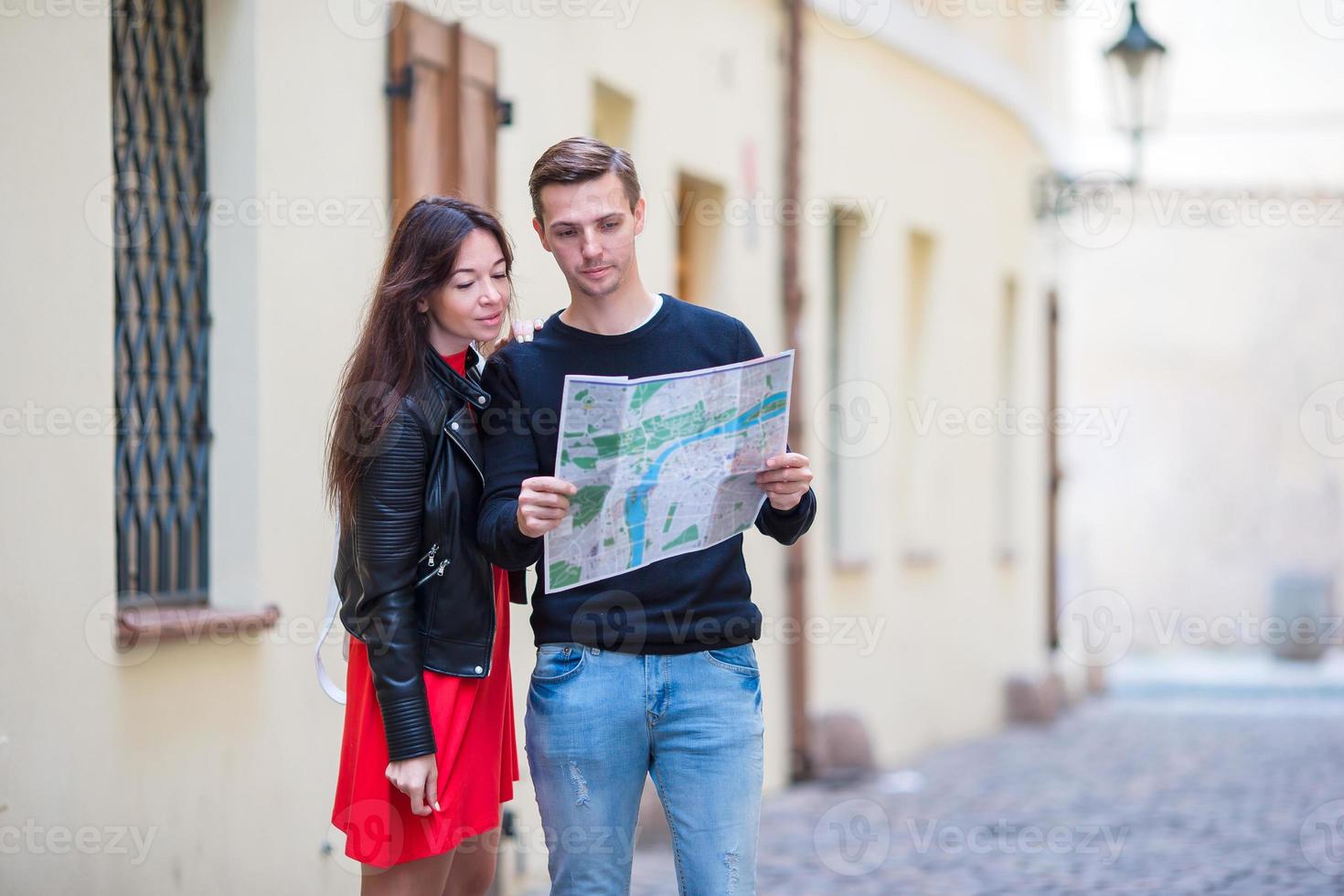 Young couple traveling on holidays outdoors smiling happy. Caucasian family with city map in search of attractions photo