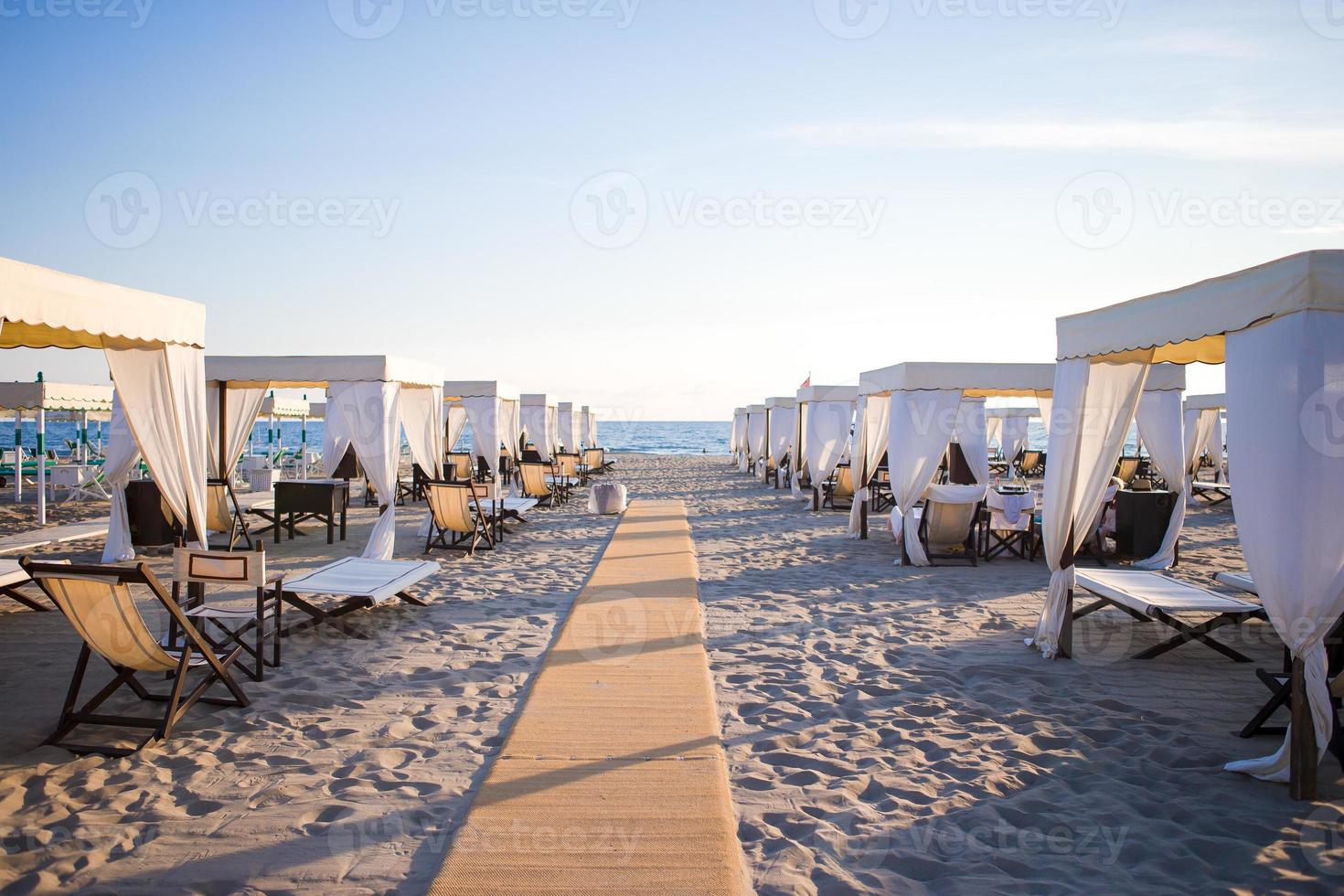 Wooden sunbeds in front of a turquoise sea in the evening light. Sunbeds in famous italian sand beach at Forte dei Marmi photo