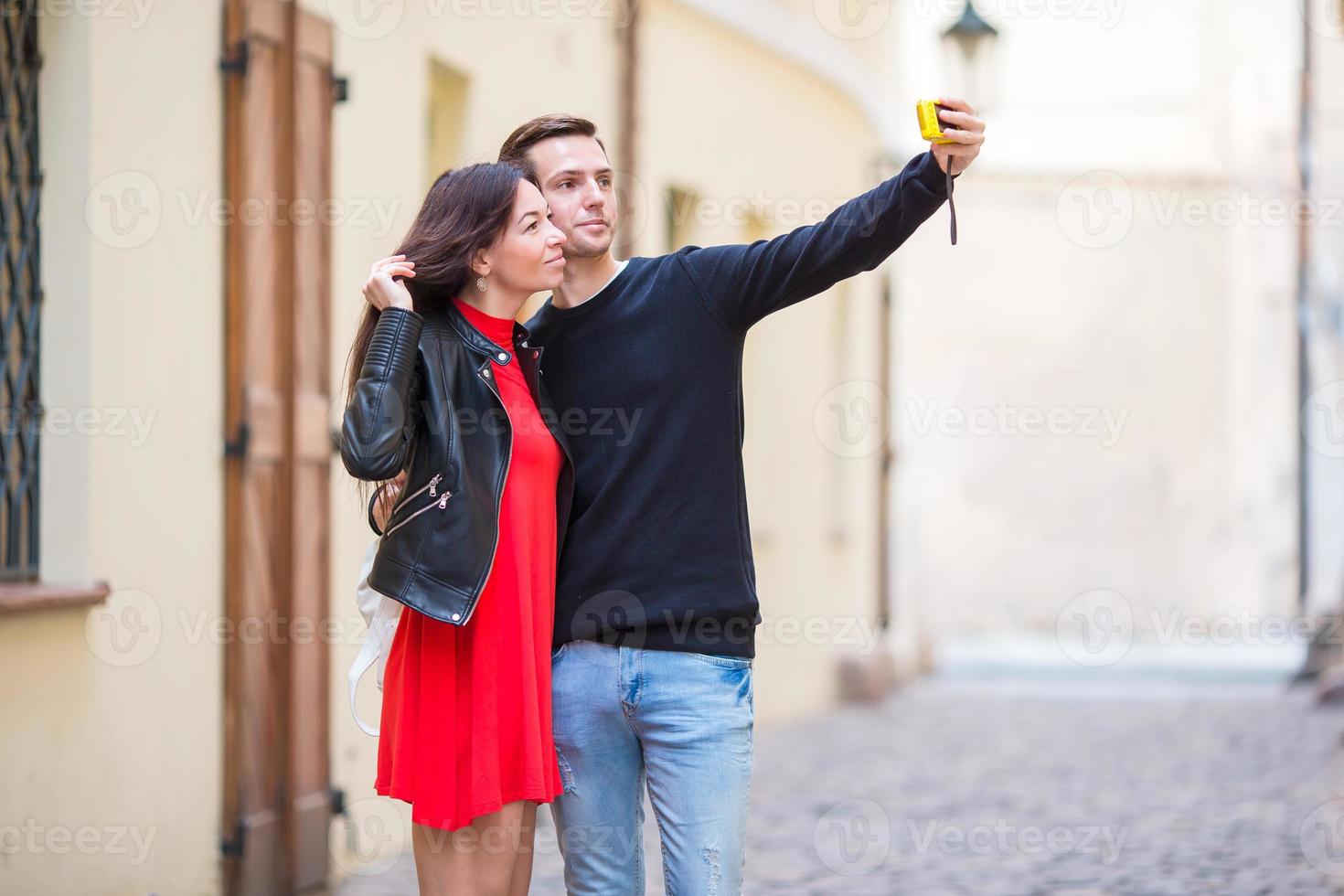 Young couple traveling on holidays in Europe smiling happy. Caucasian family making selfie in european empty old streets photo