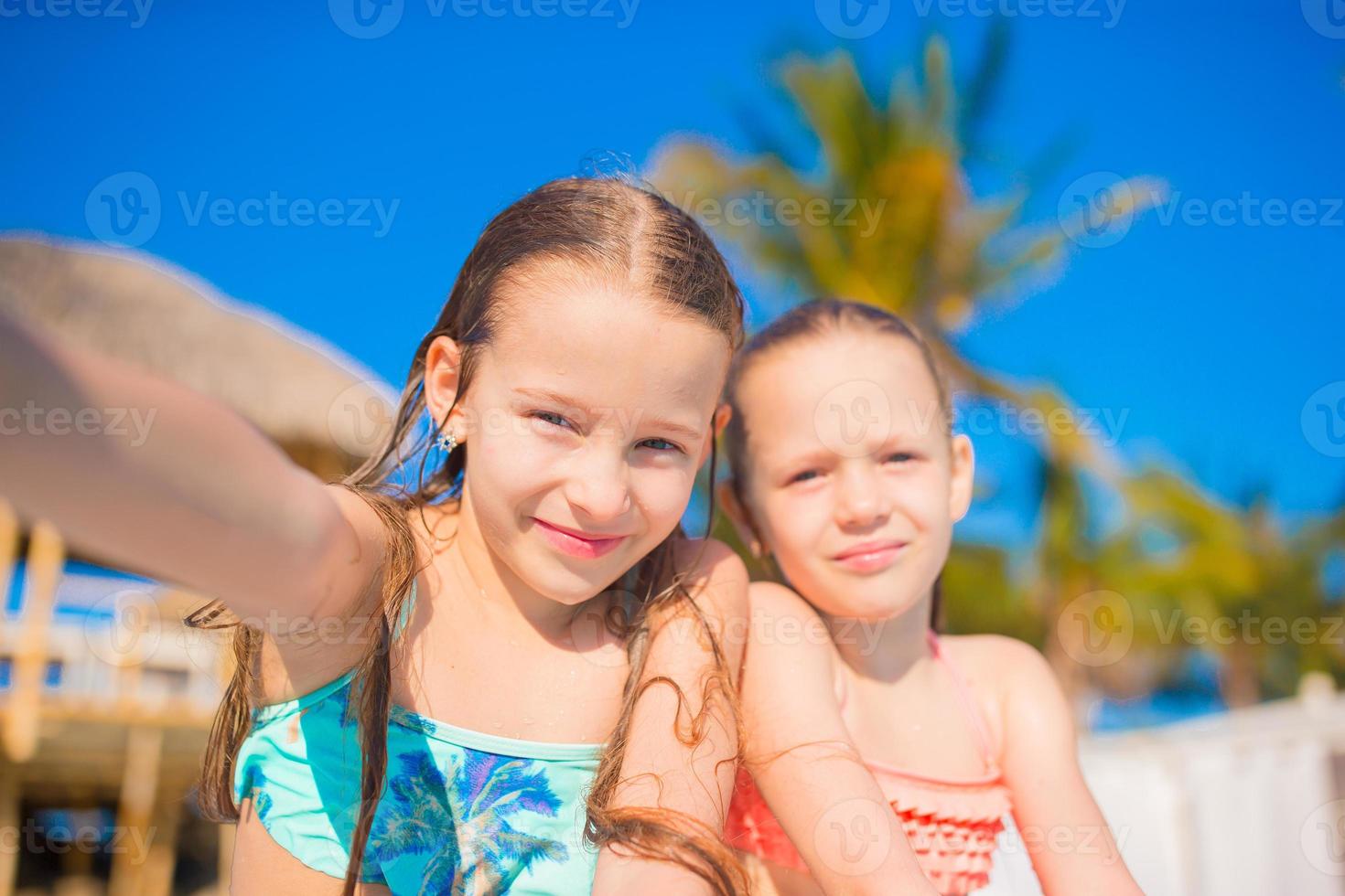 Adorable little girls playing in outdoor swimming pool. Cute kids take selfie. photo