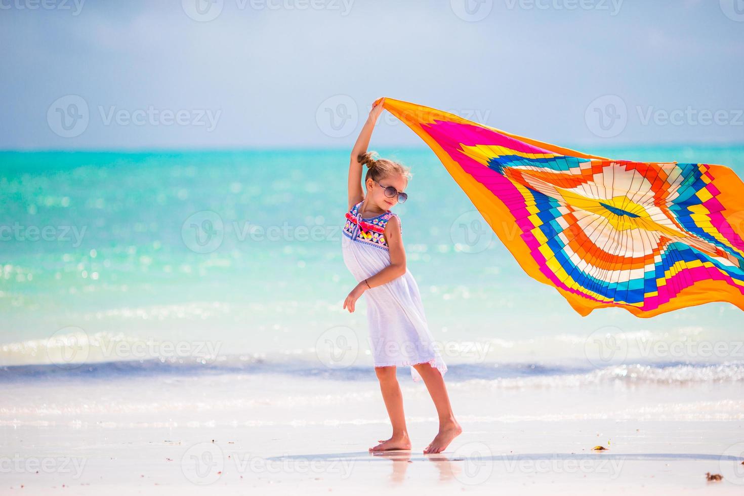 Little girl have fun with beach towel during tropical vacation photo