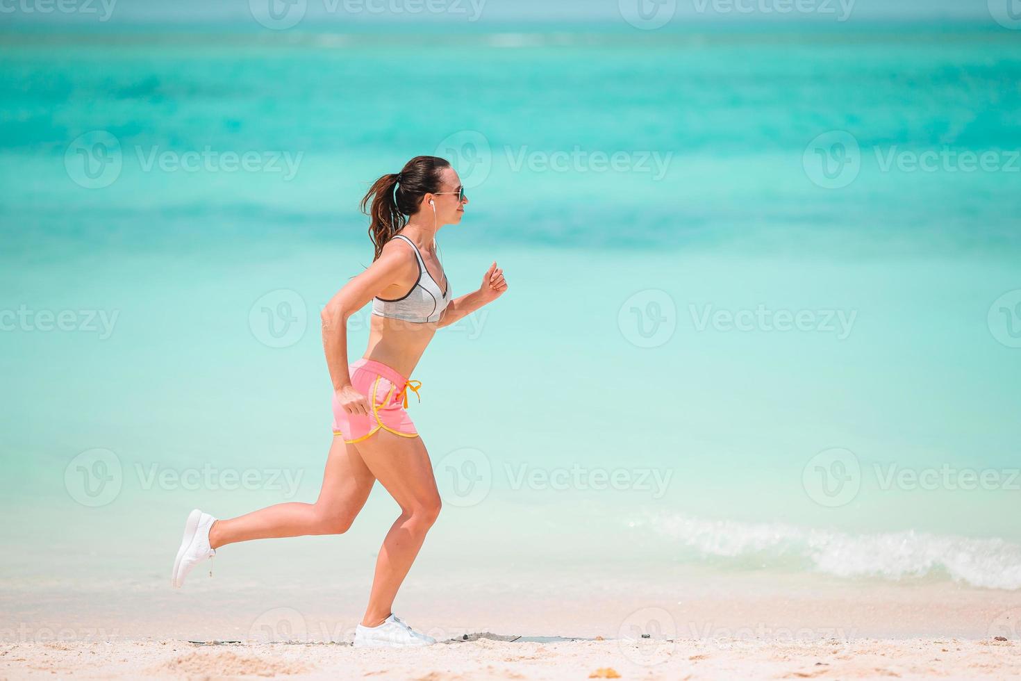 Fit young woman doing exercises on tropical white beach in her sportswear photo