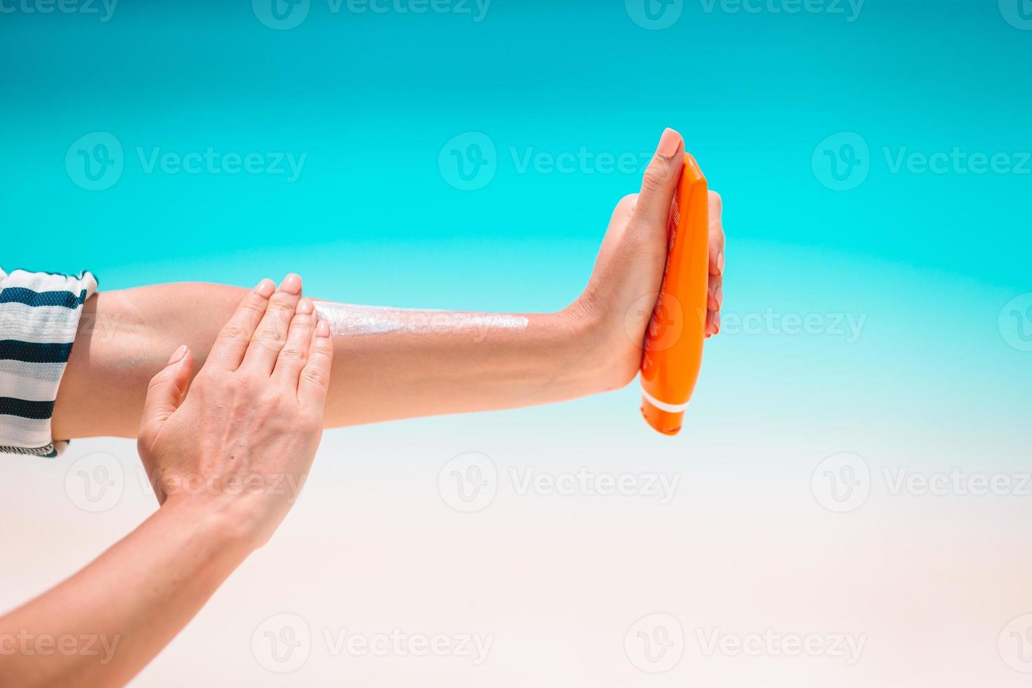 Beautiful young woman holding a suncream lying on tropical beach photo