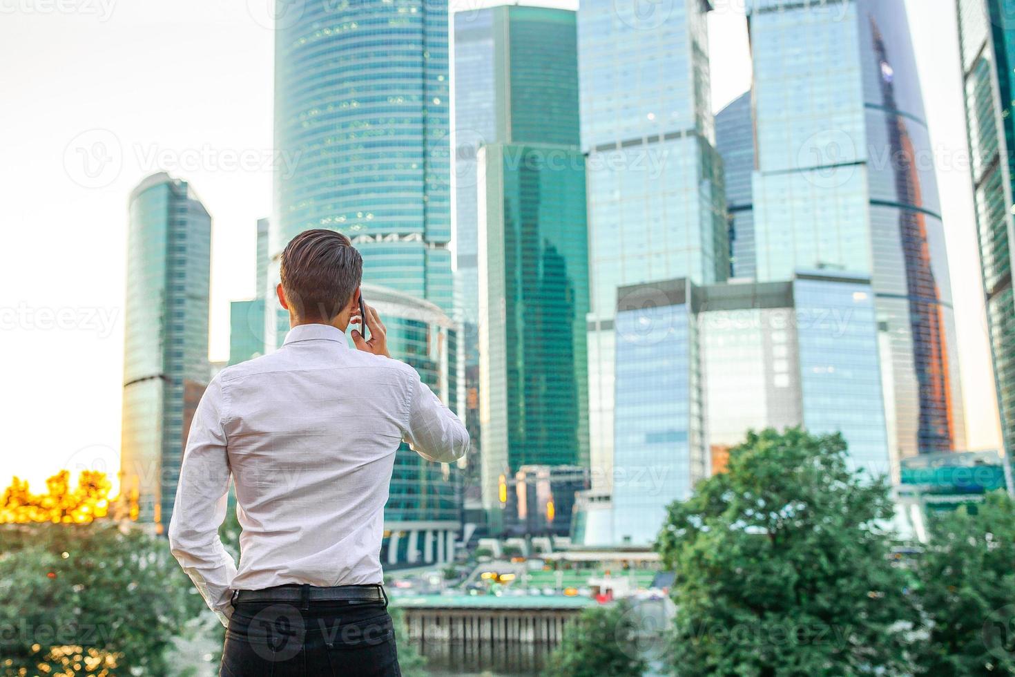 Back view of businessman looking on copy space while standing against glass skyscraper photo