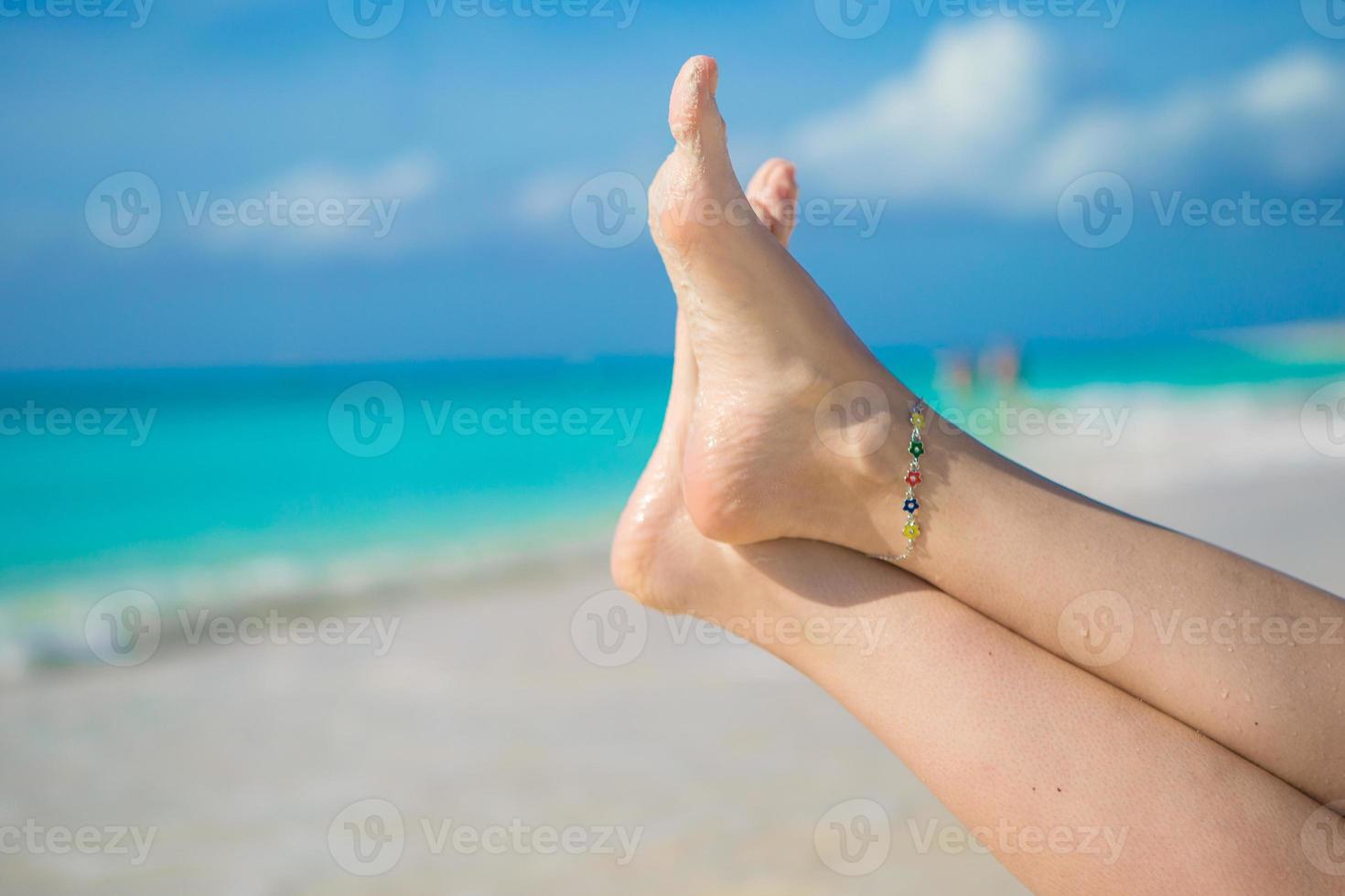 Close up of female feet on white sandy beach photo