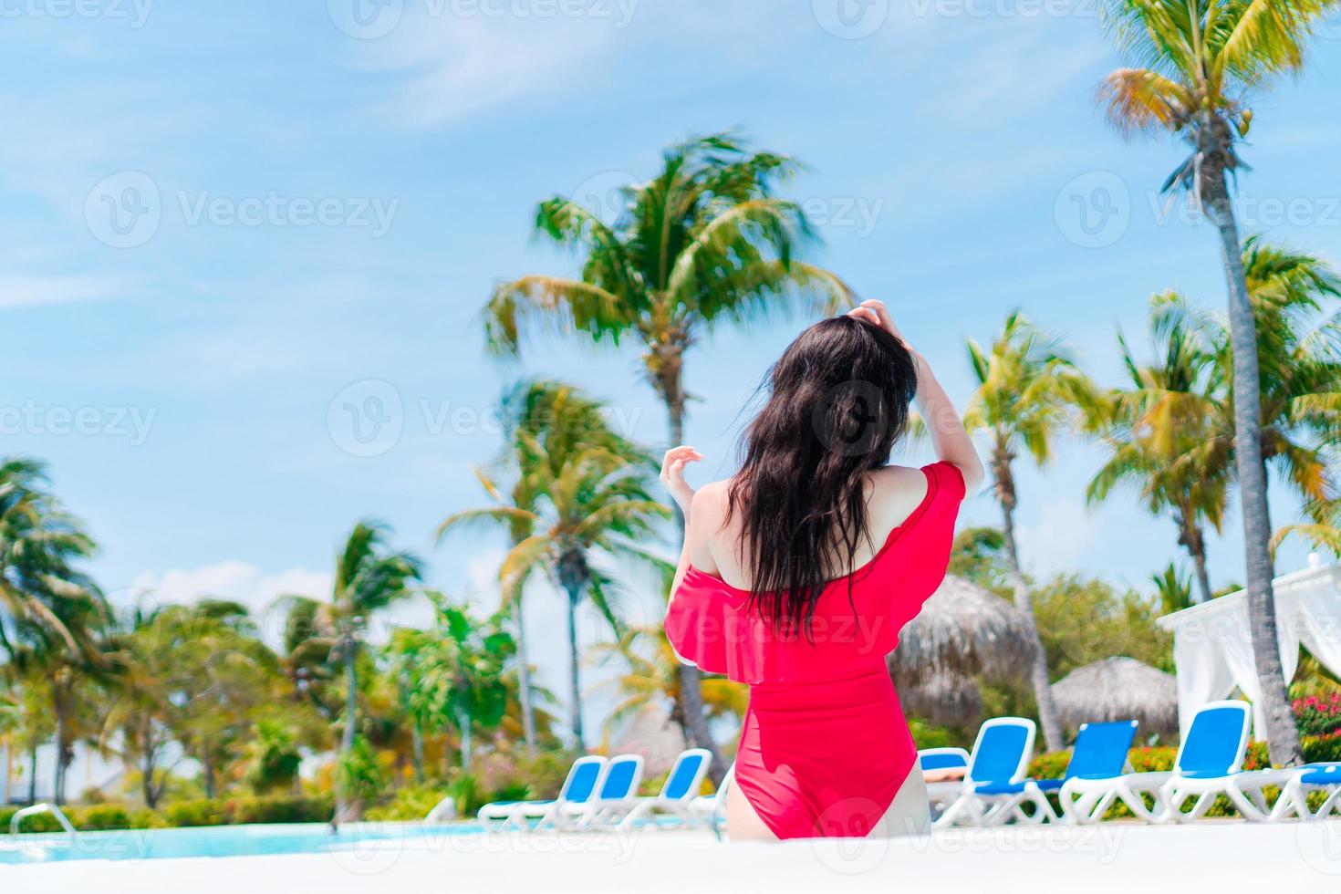Beautiful young woman relaxing in swimming pool. Happy girl in outdoor pool at luxury hotel photo