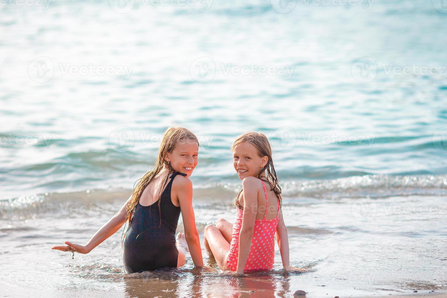 Little happy funny girls have a lot of fun at tropical beach playing together. photo