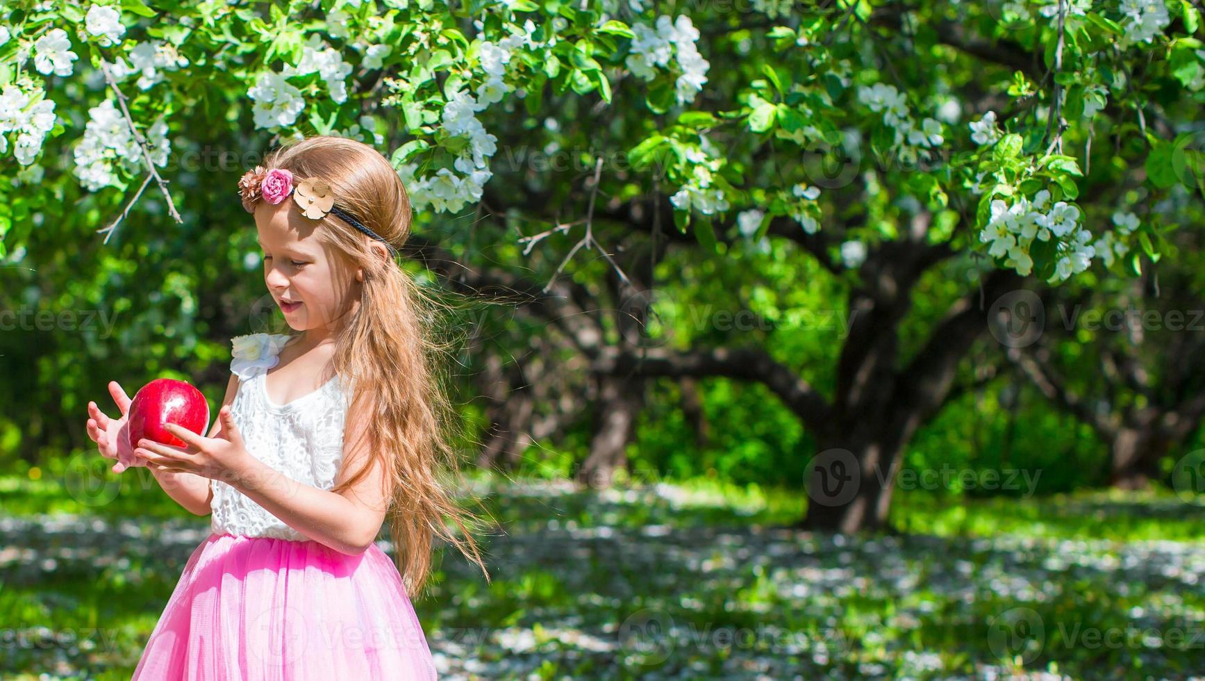 Happy little adorable girl in blossoming apple tree garden photo