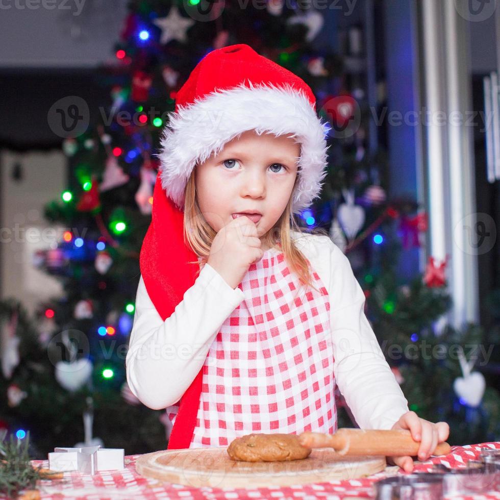 Portrait of little girl with rolling pin baking gingerbread cookies for Christmas photo