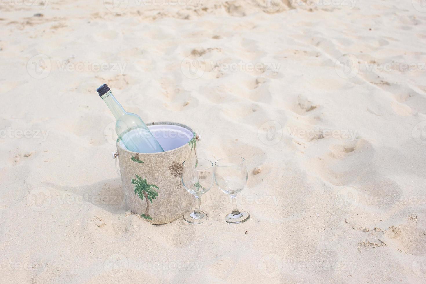 Bottle of wine and two glasses on sandy beach photo