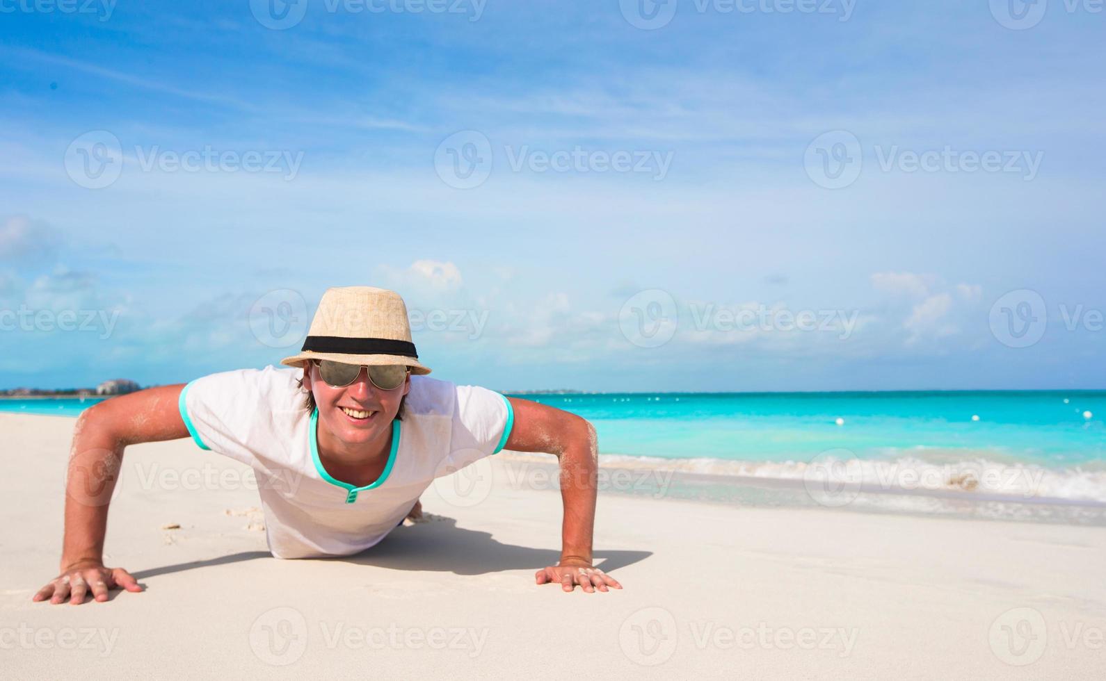 Young man doing push ups on sandy beach photo