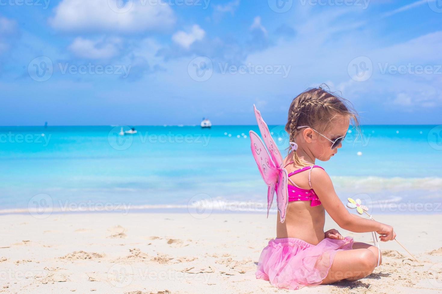 Adorable little girl with wings like butterfly on beach vacation photo