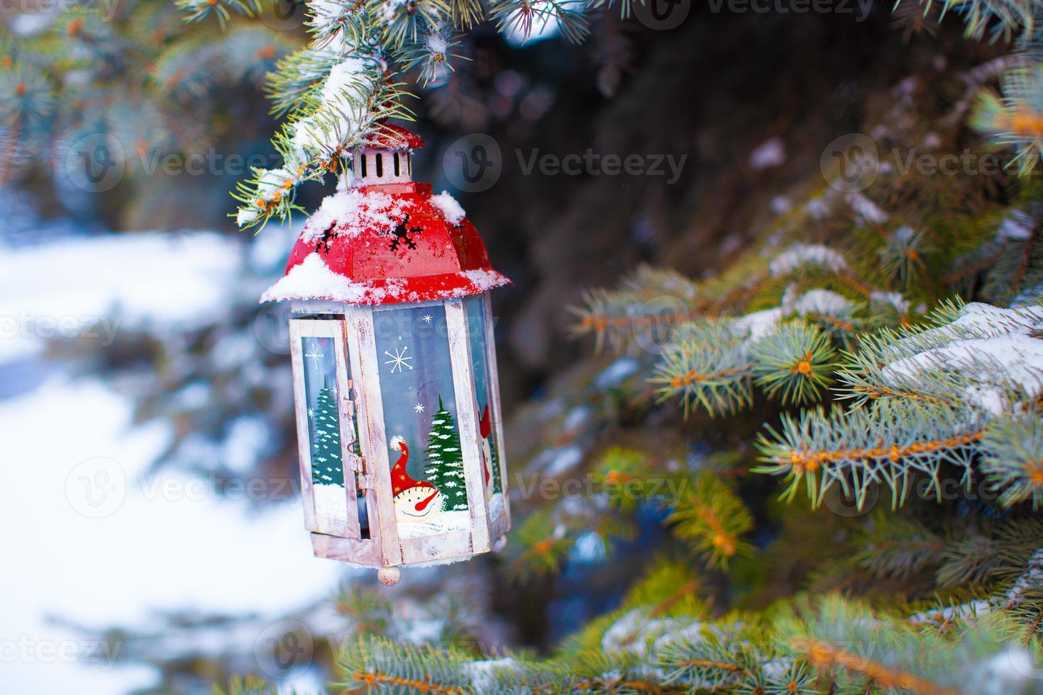 Decorative Christmas lantern on fir branch in snow winter day photo
