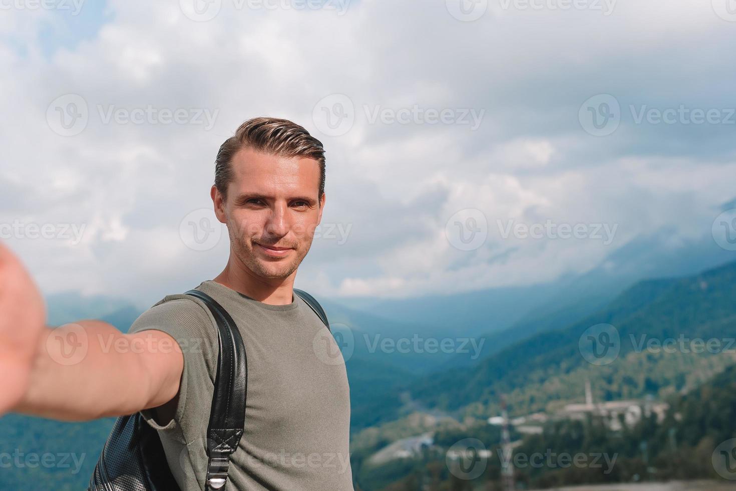 Man tourist taking selfie in mountains outdoors photo