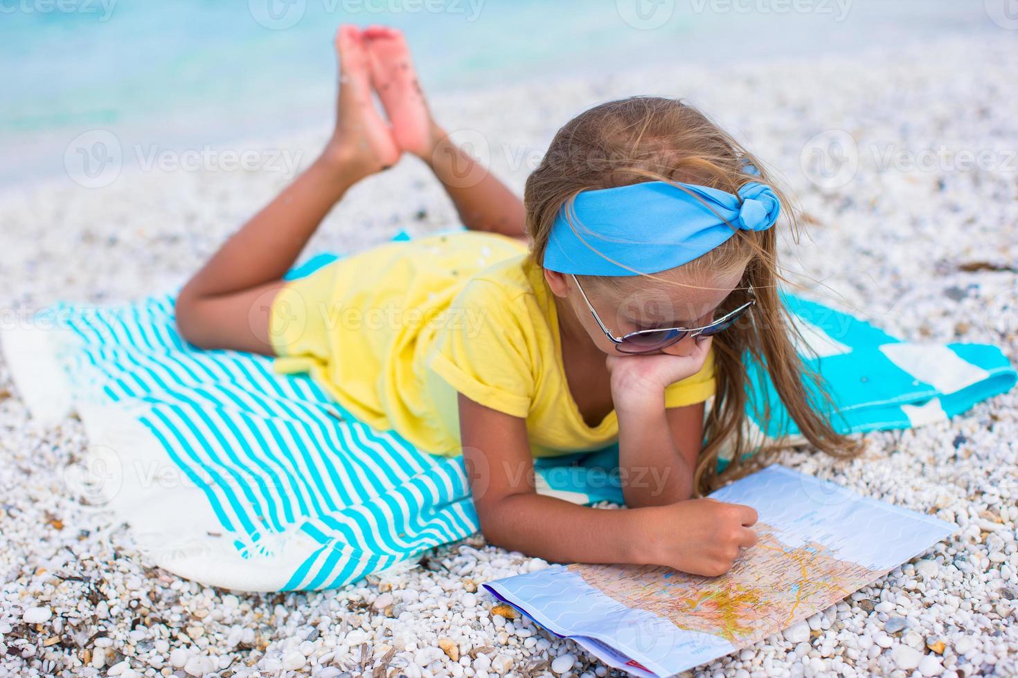 Adorable little girl with map find the way on tropical beach vacation photo