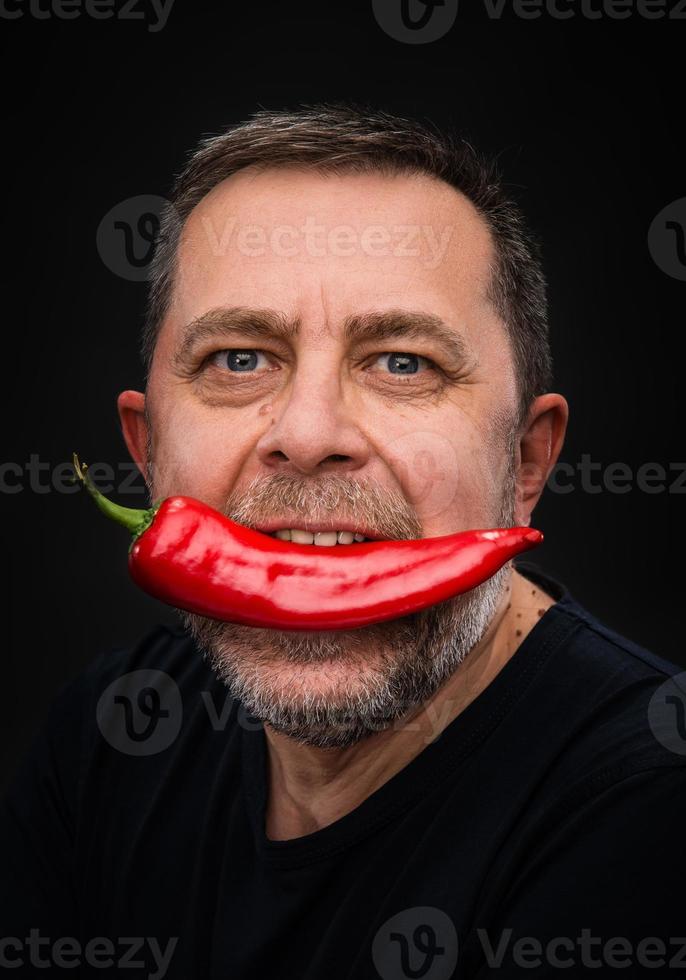 elderly man with red pepper in his mouth photo