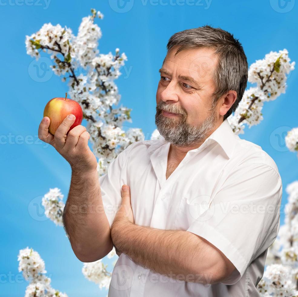 hombre de mediana edad sosteniendo una manzana roja foto